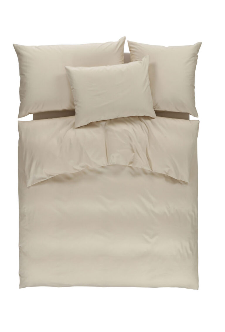 Ein ordentlich gemachtes Bett mit einem beigen Bettbezug und vier passenden beigen Kissen, von oben gesehen vor einem weißen Hintergrund.