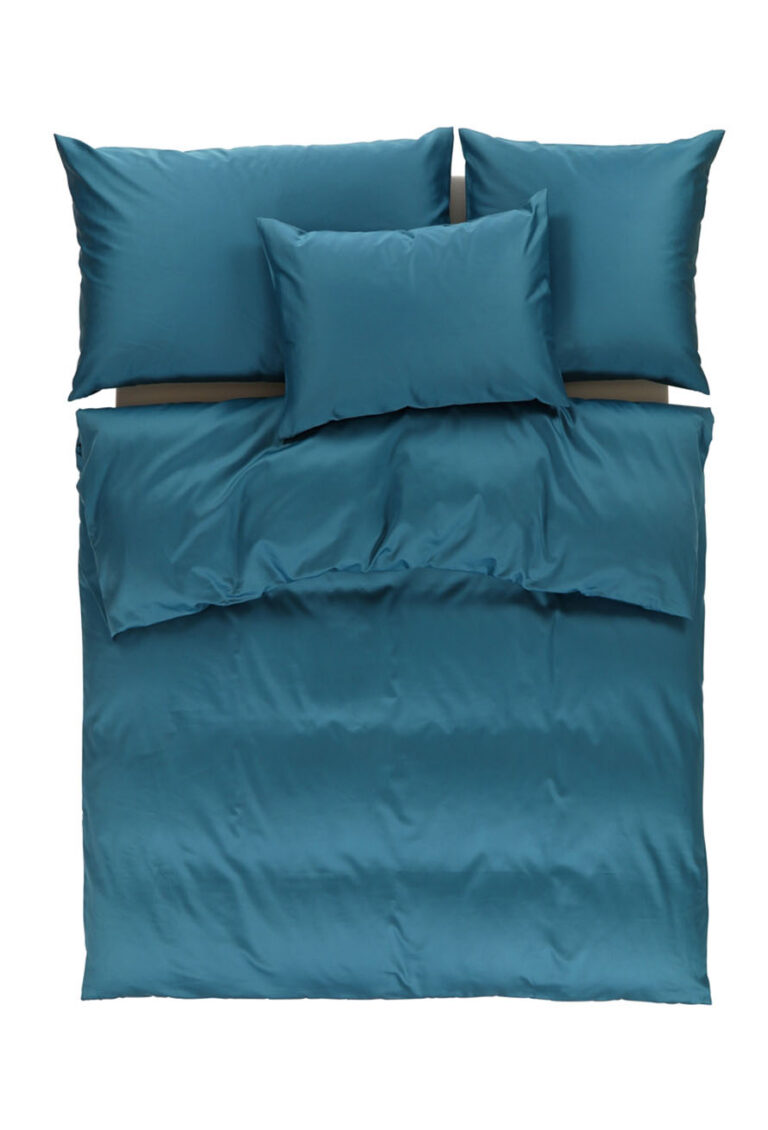Ein gemachtes Bett mit blaugrüner Bettwäsche, einschließlich einer Bettdecke, zwei großen Kissen am Kopfende und einem kleineren Kissen davor, von oben gesehen auf weißem Hintergrund.
