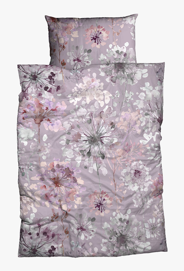 Ein Bettwäscheset mit einem Kissen und einer Bettdecke mit zartem lila Hintergrund und einem Blumenmuster in Rosa-, Weiß- und Grautönen, das einen zarten und eleganten Look erzeugt.