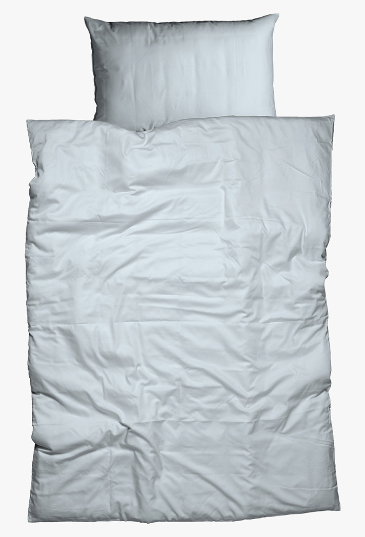 Ein ordentlich gemachtes Bett mit einem weißen Kissen und einer weißen, leicht zerknitterten Bettdecke, von oben betrachtet auf einem schlichten Hintergrund.